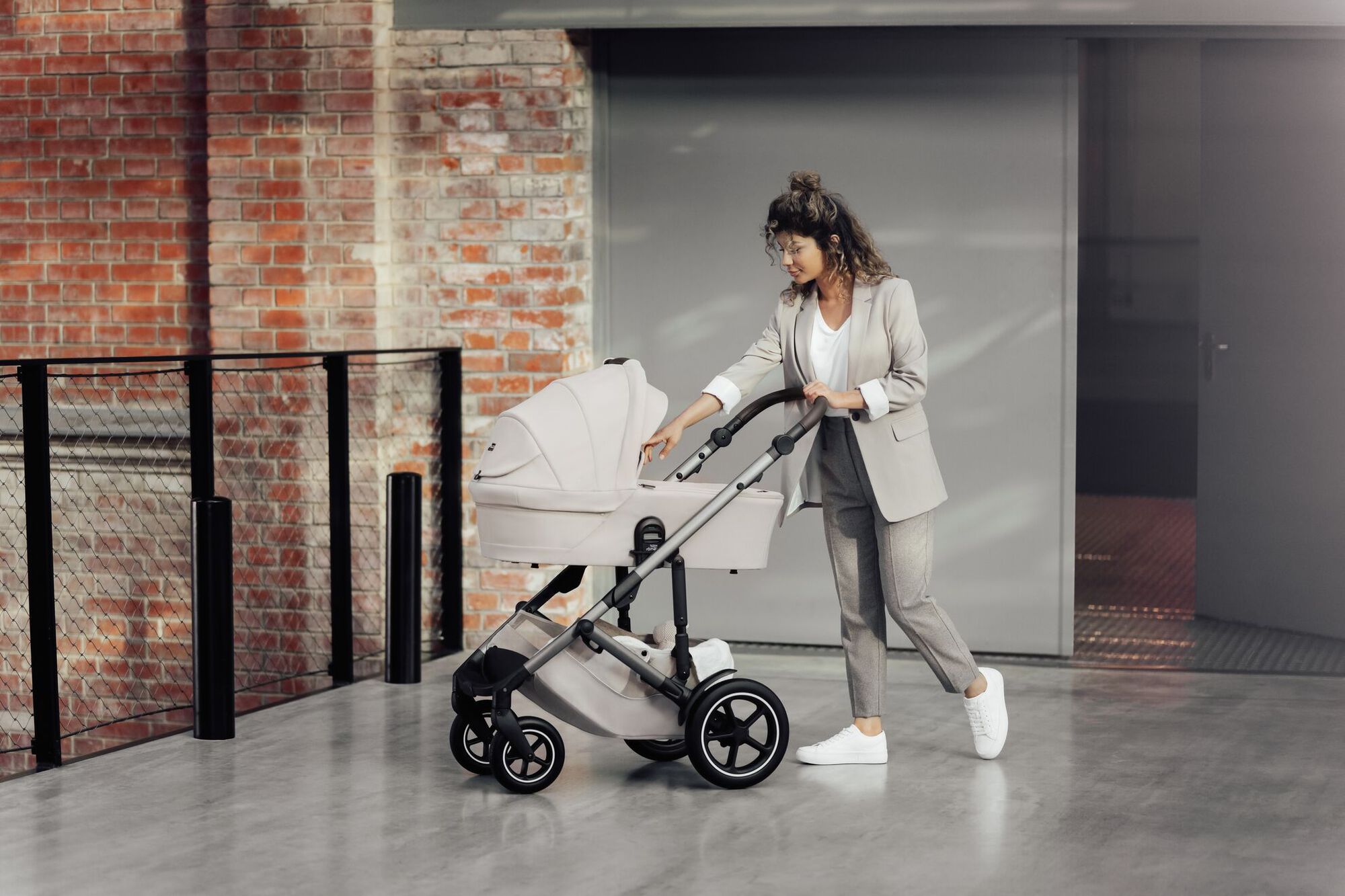 Ouder duwt een SMILE 5Z kinderwagen met reiswieg en controleert voorzichtig de baby.